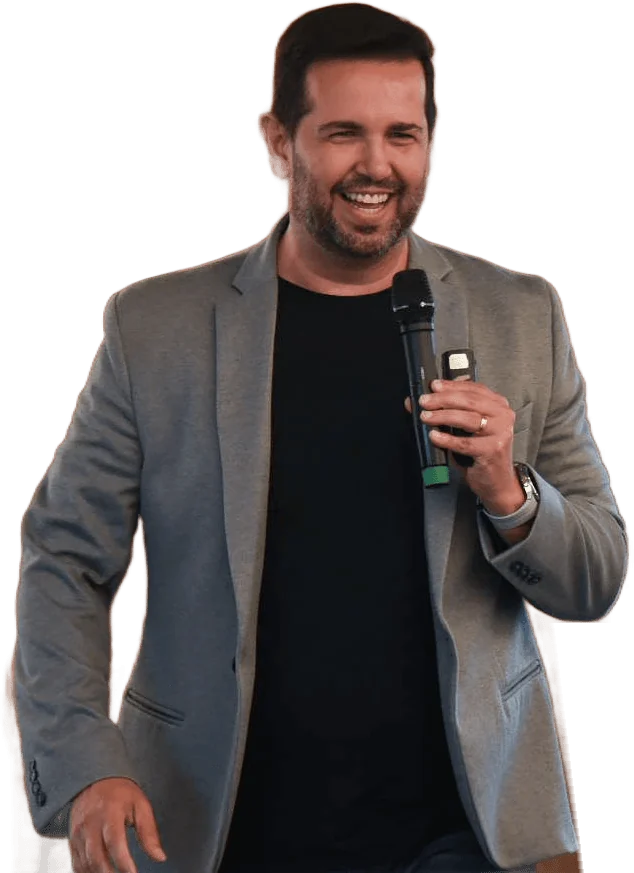 Dennis Penna sorrindo no palco, com microfone na mão